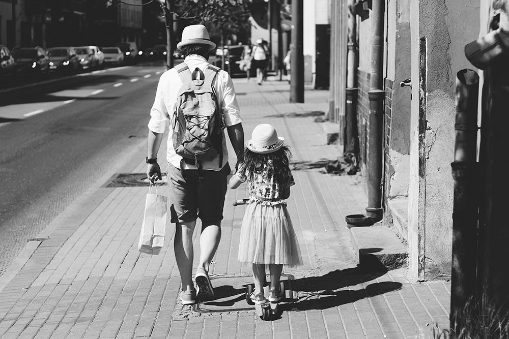 Schwarz-weiß-Foto von einem Vater mit seiner Tochter die durch eine Stadt spazieren mit Retro-Feeling