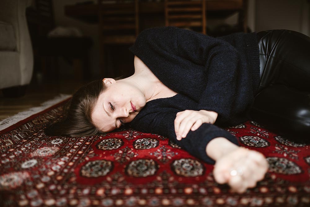 Frau liegt zerstört traurig und energielos am Boden auf einem roten Teppich
