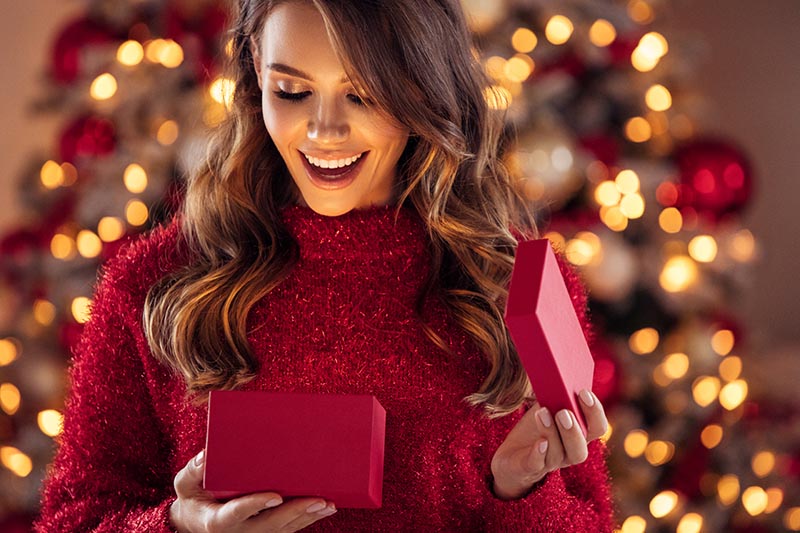 Single-Frau an Weihnachten öffnet ein Geschenk