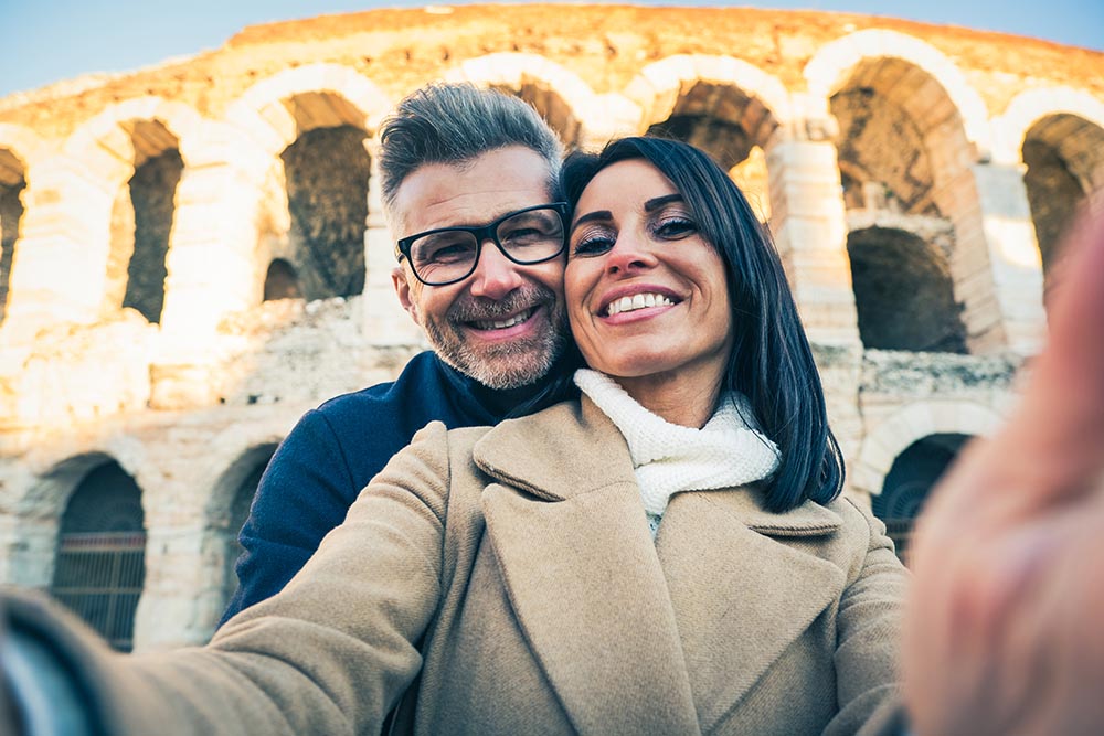 Lächelndes Paar mittleren Alters macht vor dem Kolosseum in Rom ein Selfie