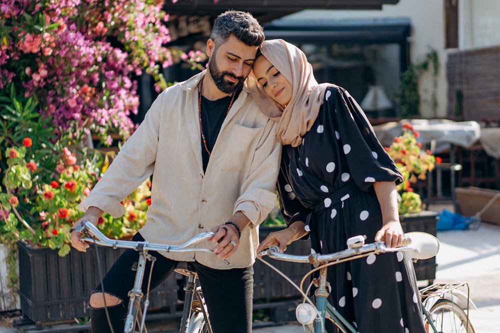 Mann und Frau lehnen beim Fahrradfahren verliebt aneinander und genießen den gemeinsamen Moment