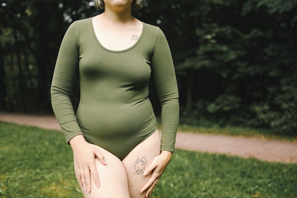 Frau in grünem Body zeigt ihren Körper selbstbewusst im Rahmen der Body Positivity Bewegung