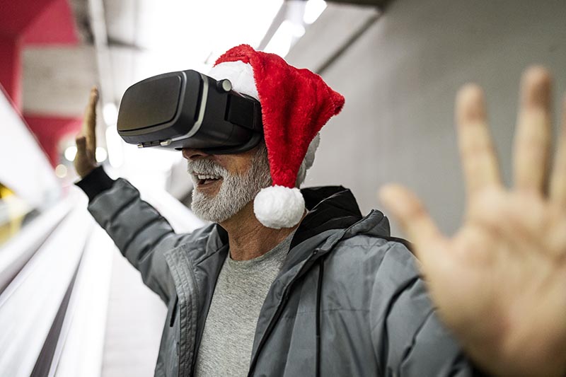 Älterer Mann spielt an Weihnachten mit einer VR-Brille Videospiele