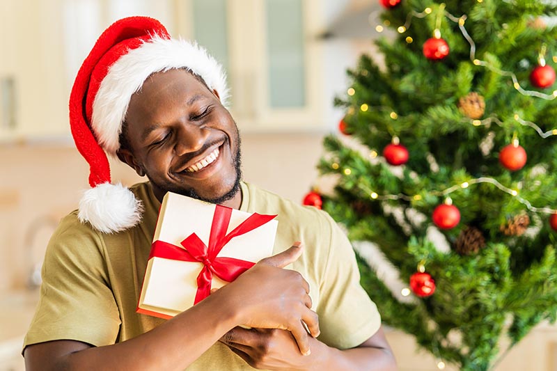 Junger schwarzer Mann freut sich über Weihnachtsgeschenk