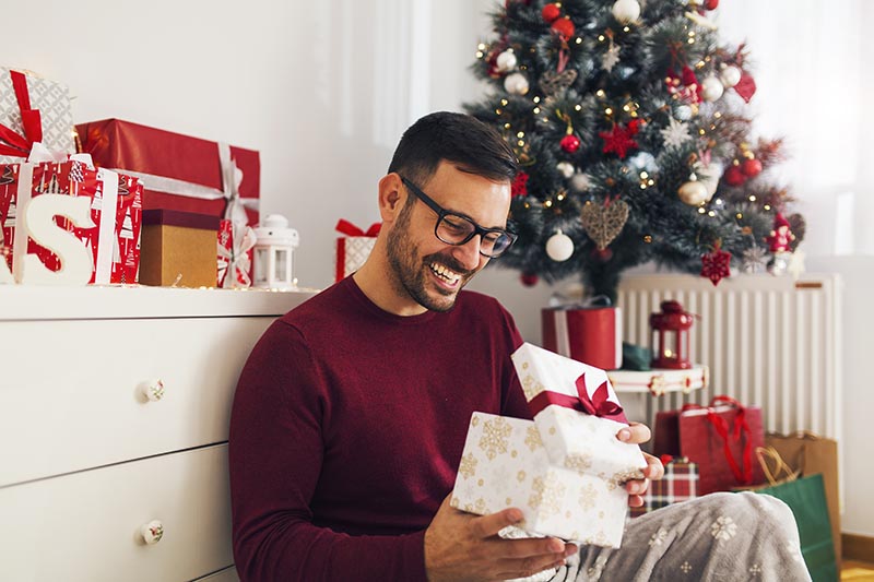 Attraktiver junger Mann freut sich über ein Weihnachtsgeschenk