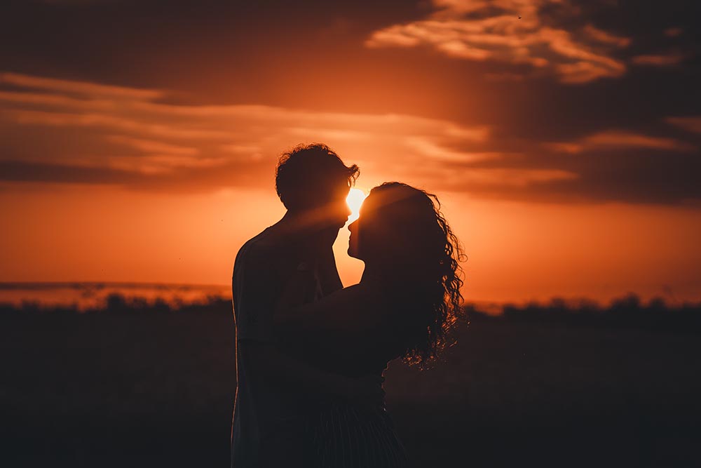Verliebtes Paar vor romantischem Sonnenuntergang am Strand zum Valentinstag